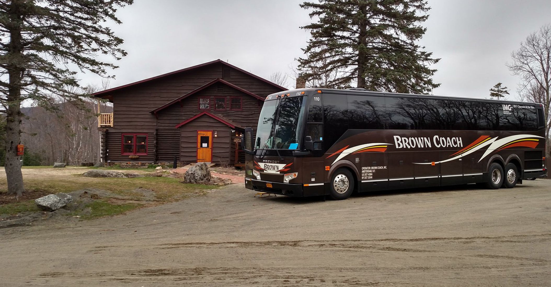 Brown Coach bus parked in front of a cabin