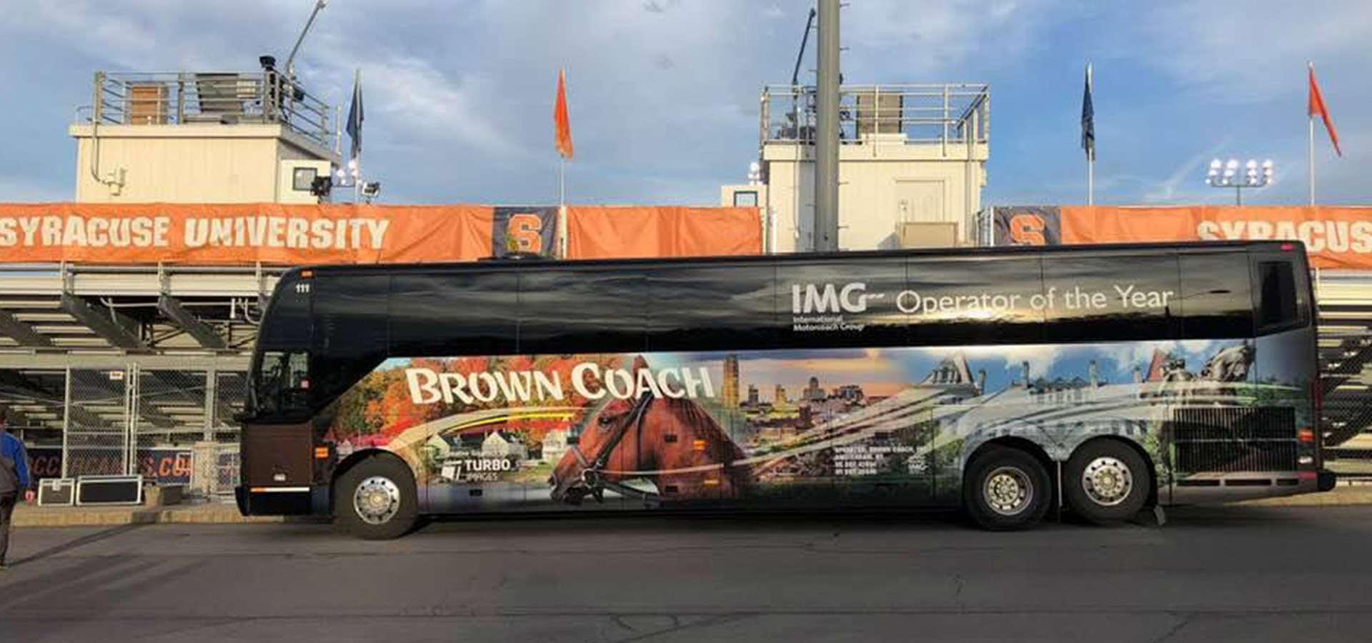 Brown Coach bus parked outside Syracuse University